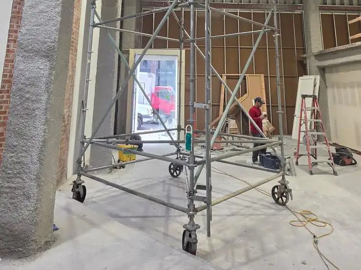 Interior system scaffold reaching a high ceiling inside a retail space under renovation