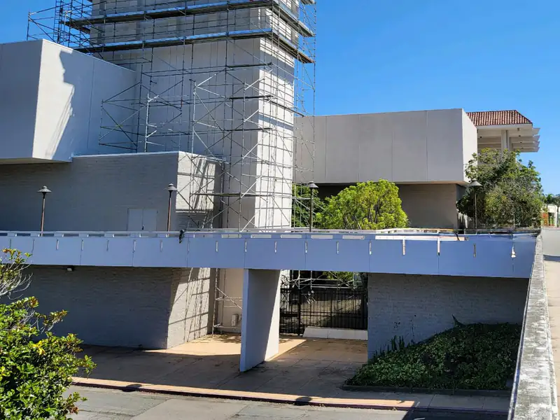 Tall scaffold tower rising beside a modern commercial building with a flat roof