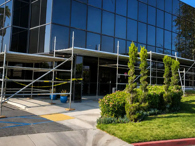 Scaffold canopy with a solid deck covering the entrance walkway of a glass office building